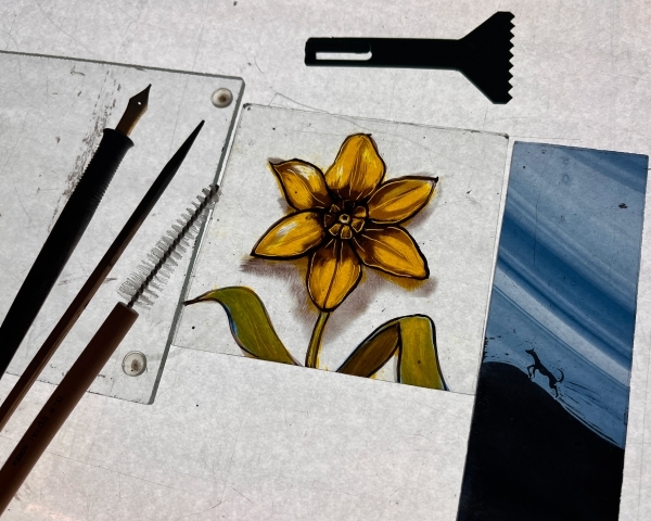 A painted stained glass daffodil and tools.
