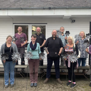 a group of 9 people holding their flower sculptures